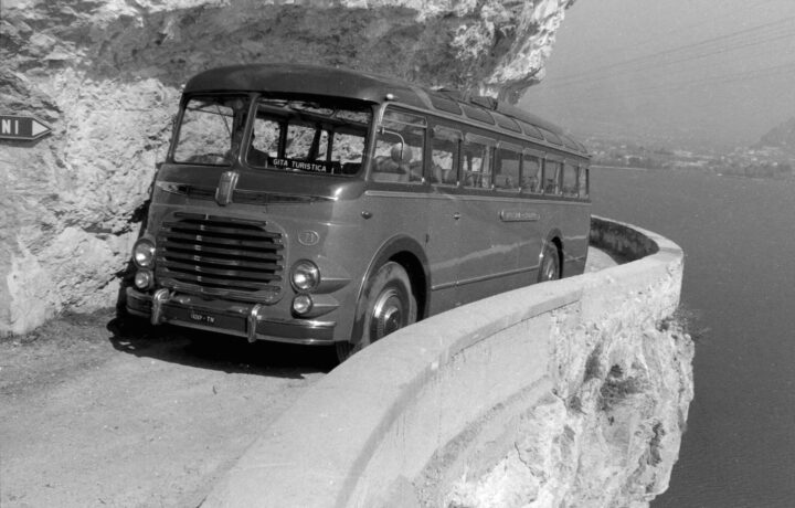 Historical 1954 photograph by Giovanni Skulina showing a passenger coach parked on the Strada del Ponale carved into the rock above Lake Garda
