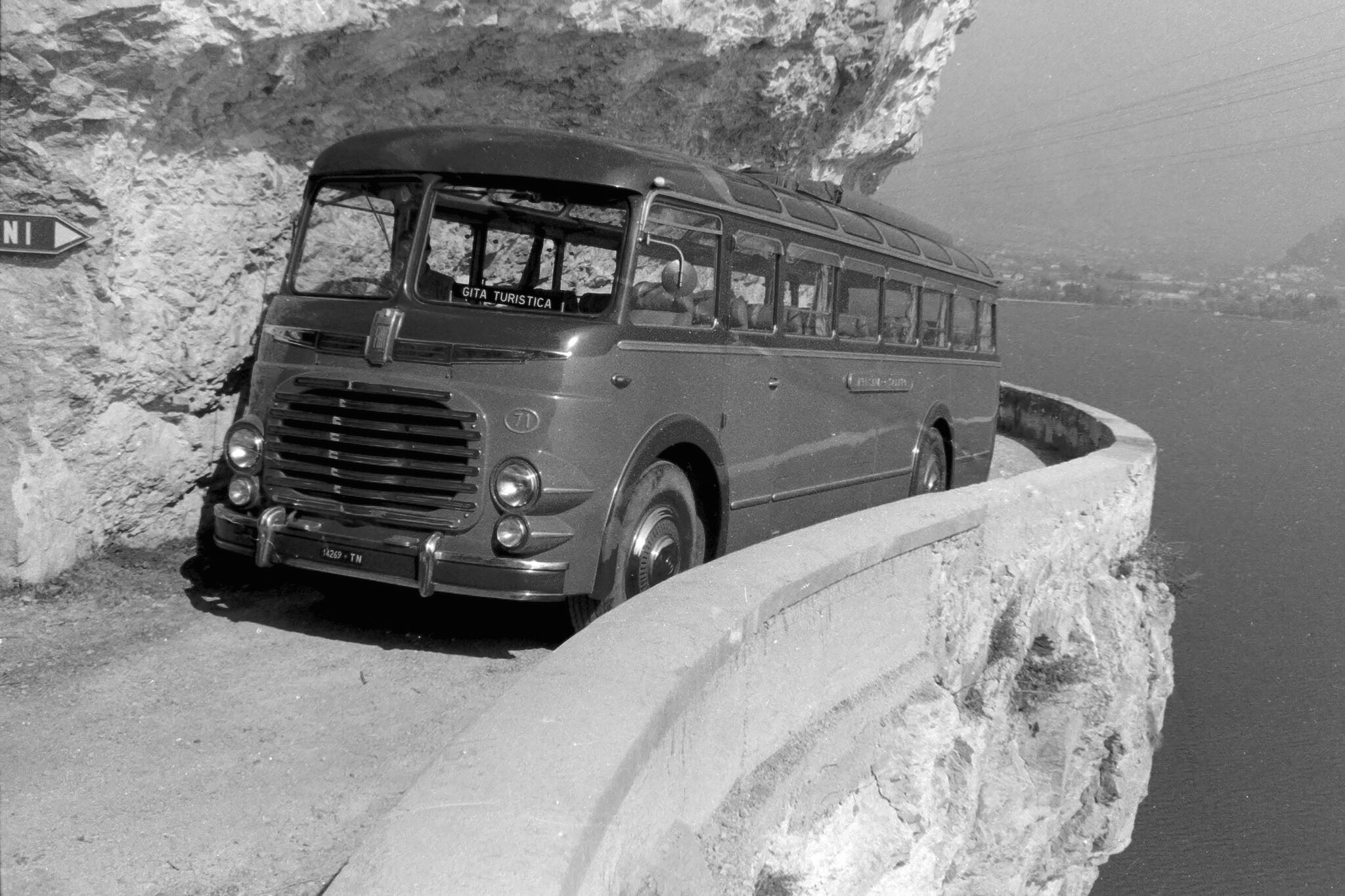 Historical 1954 photograph by Giovanni Skulina showing a passenger coach parked on the Strada del Ponale carved into the rock above Lake Garda
