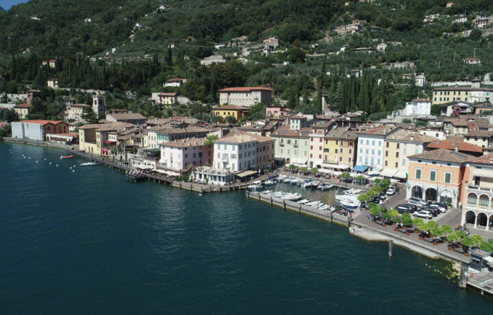 Aerial panoramic view of Gargnano lakefront and mountain road ascending towards Valvestino