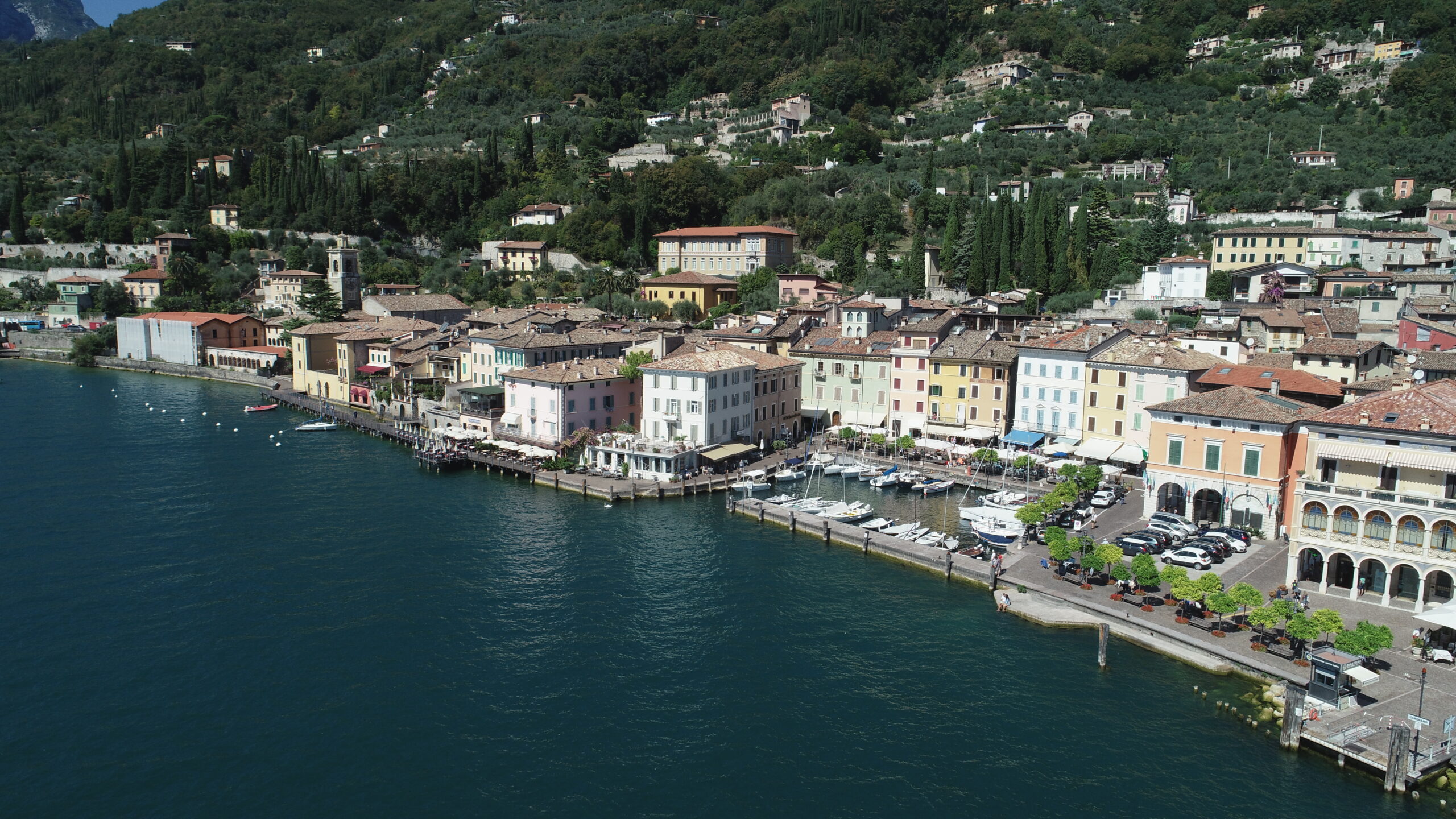 Aerial panoramic view of Gargnano lakefront and mountain road ascending towards Valvestino